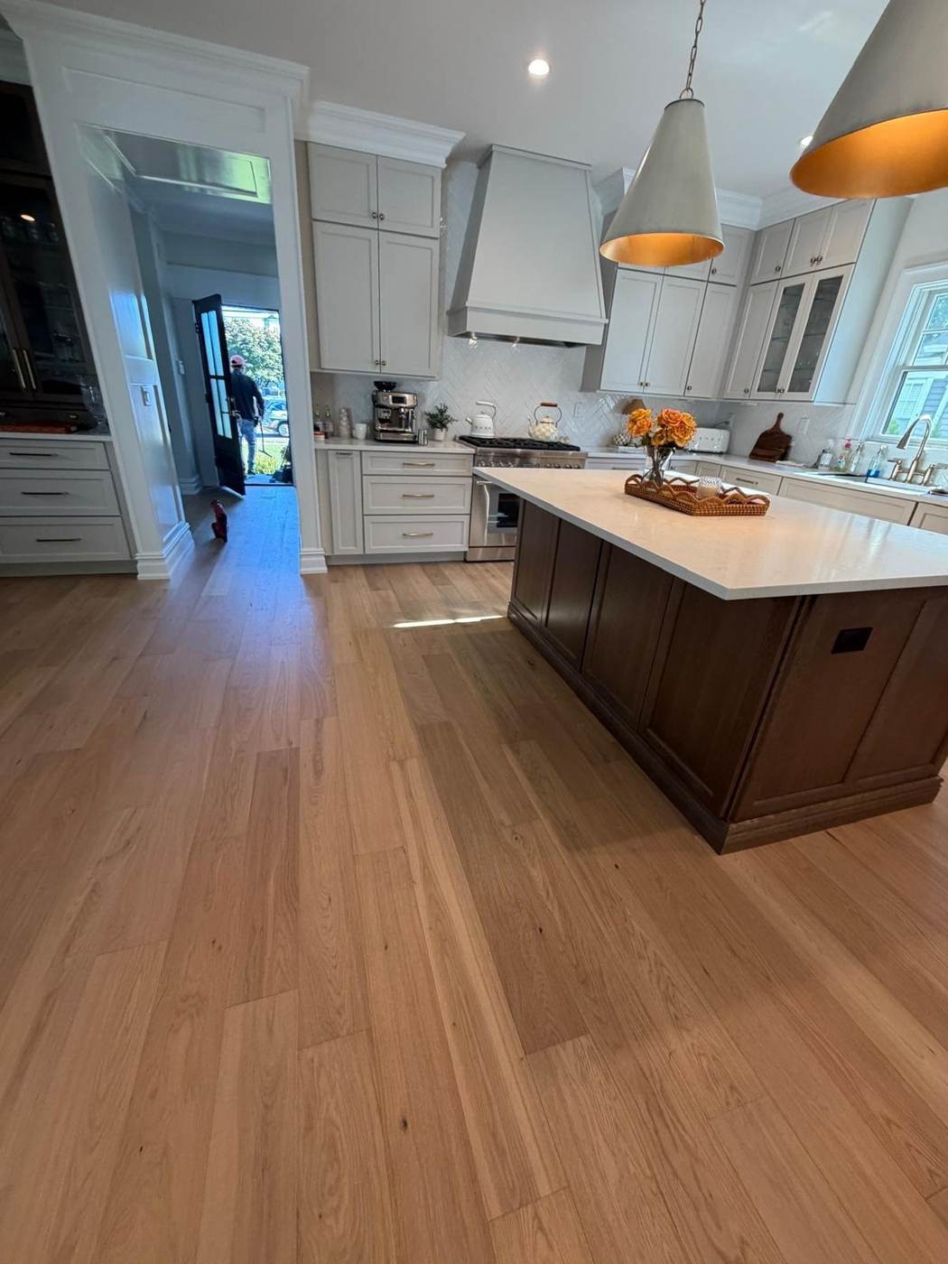 Hardwood floor through a kitchen with a dark wood island