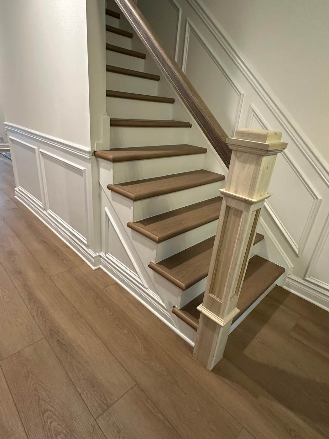 Wood stairs with white risers and a paneled wall