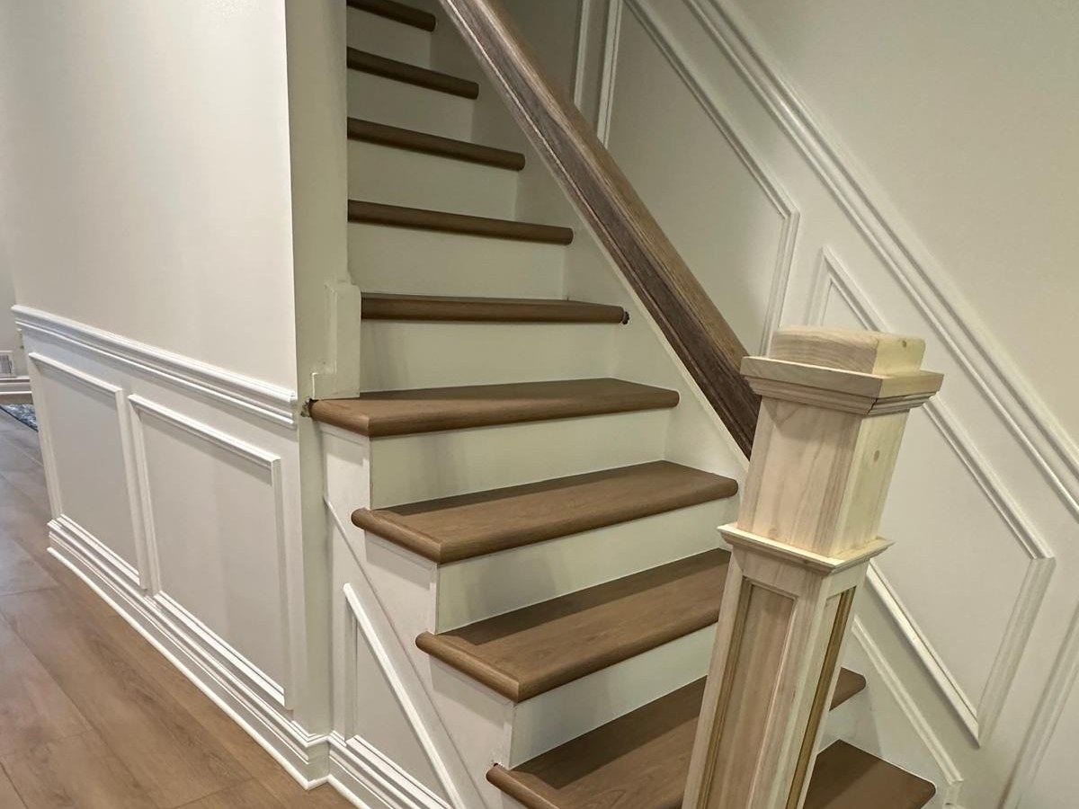 Wood stairs with white risers beside a paneled wall