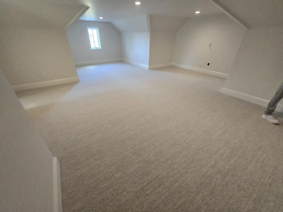 Freshly installed gray carpet in a bonus room with sloped ceilings